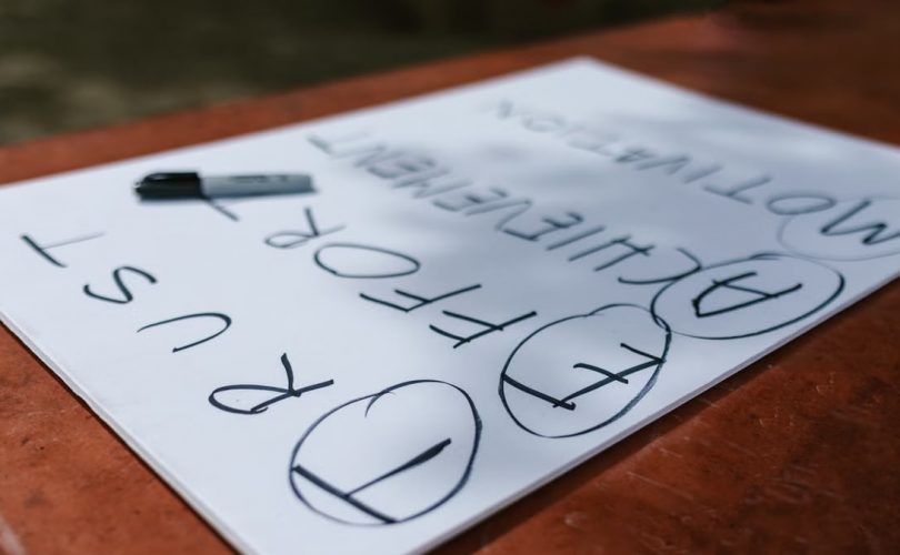 A paper with motivational words and markings placed outdoors on a table.